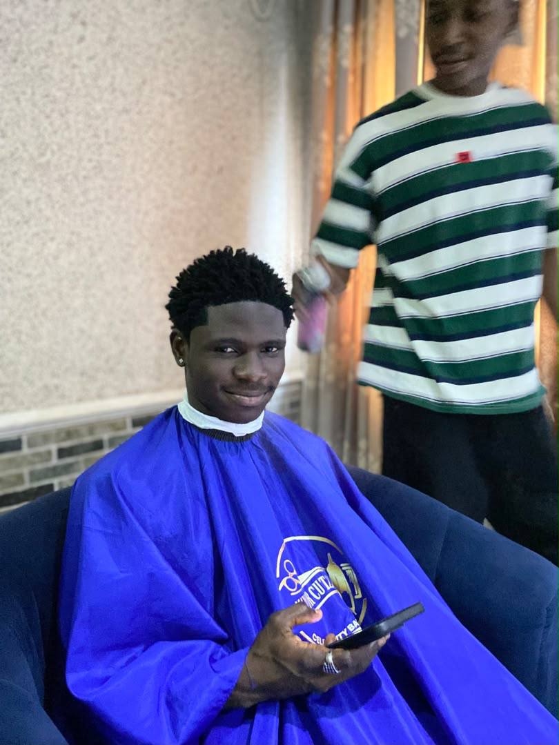 Client with a clean, finished haircut in a blue cape